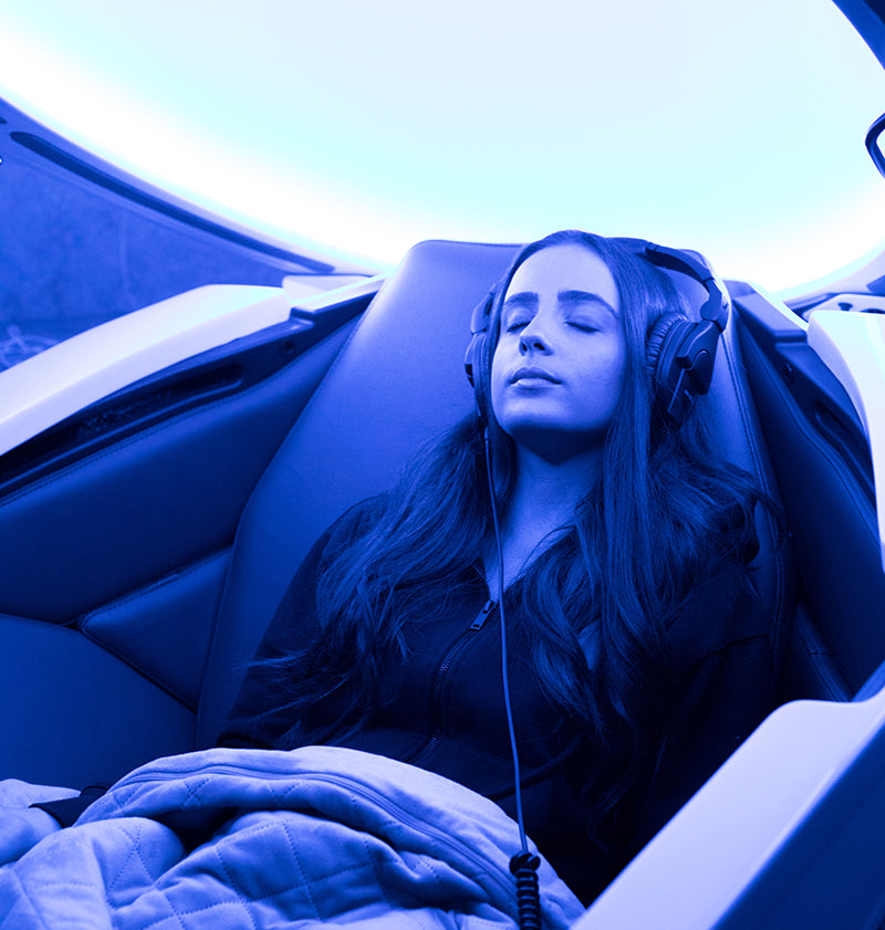Woman relaxing in blue tinted Somadome meditation pod