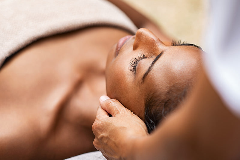 Woman laying down receiving massage therapy on her neck